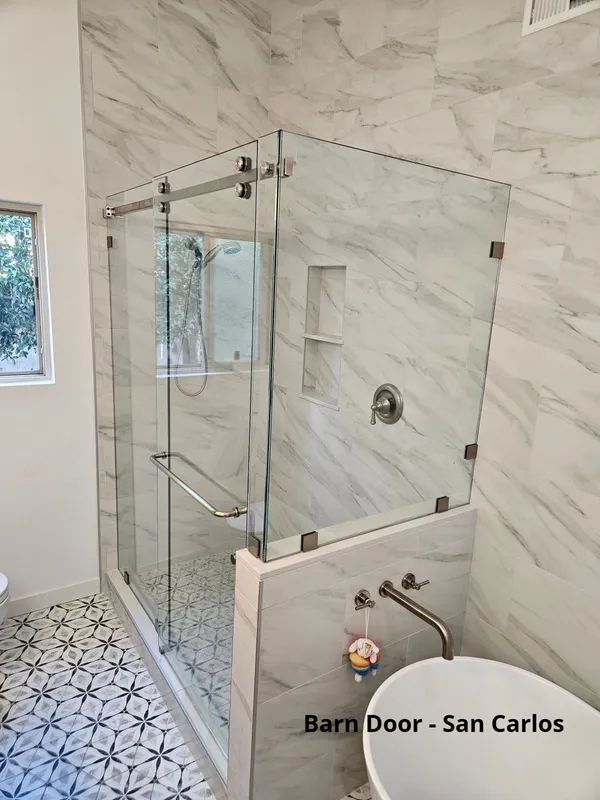 Modern bathroom with glass shower enclosure, marble-look tile, and a soaking tub.
