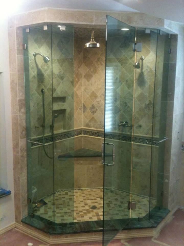 Spacious, glass-enclosed shower with multiple showerheads, tiled walls, and a built-in bench.