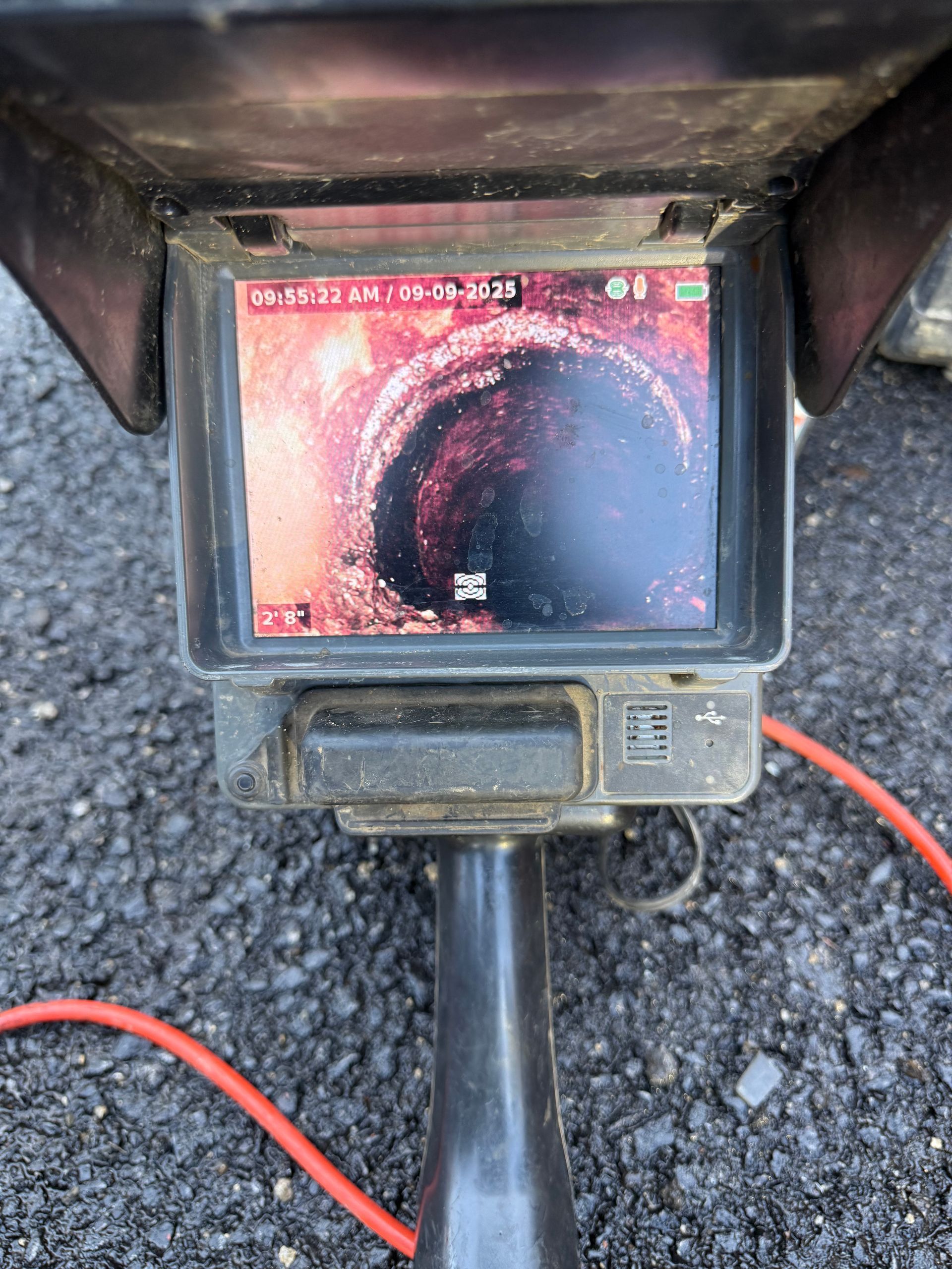 Sewer inspection camera showing a close-up view inside a pipe on a monitor.