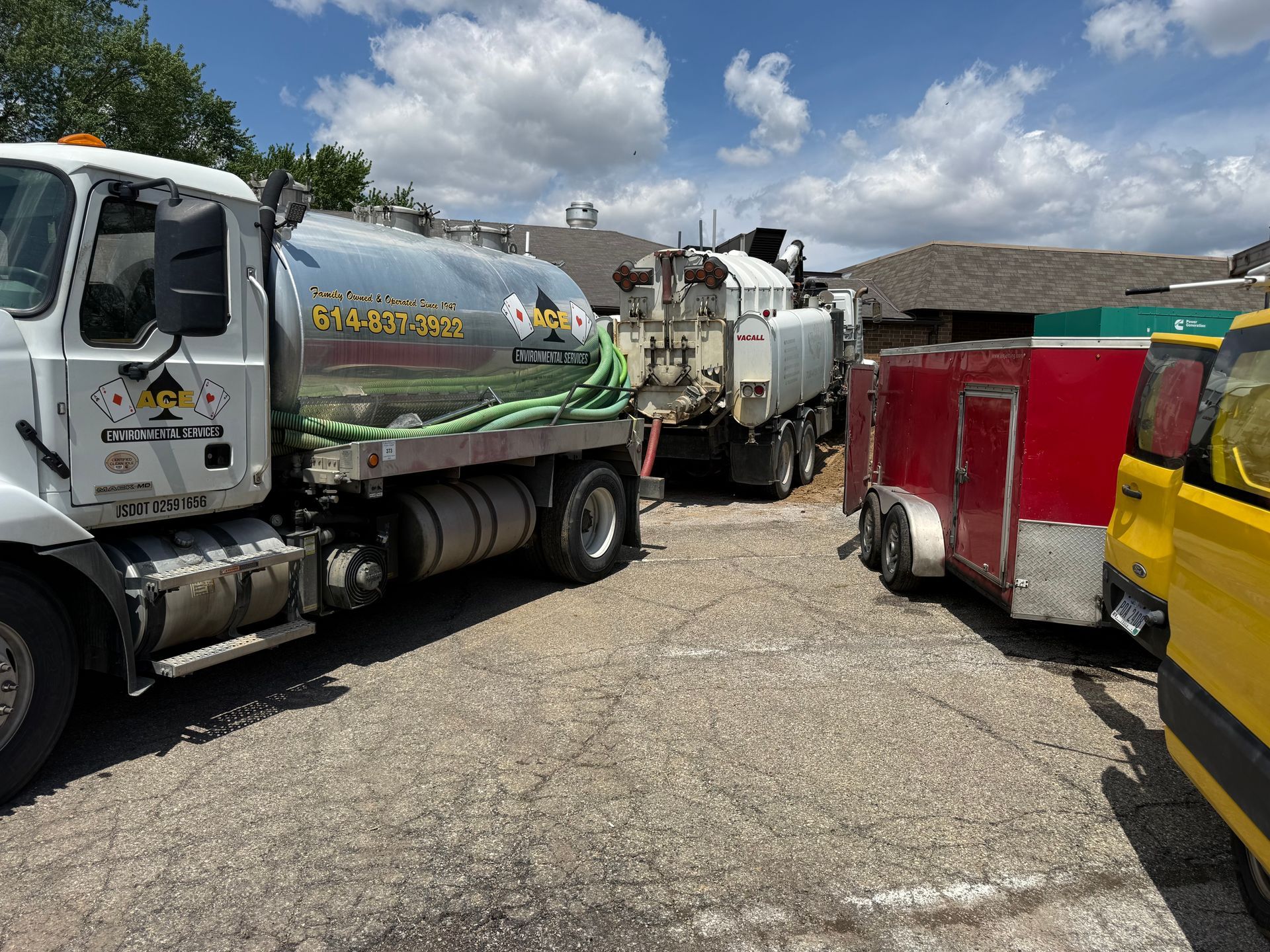 Trucks and trailers parked in a gravel lot under a partly cloudy sky.