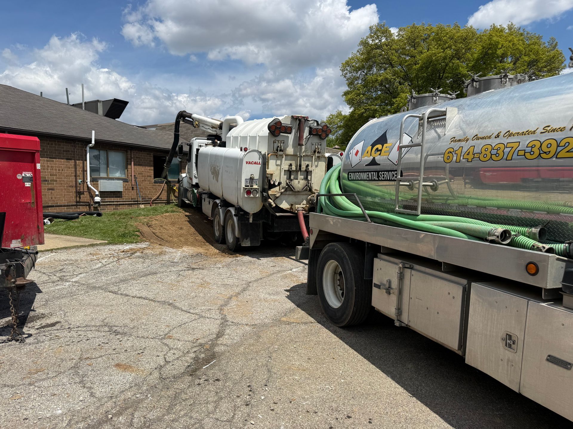Two utility trucks parked in a gravel lot beside a brick building under a cloudy sky