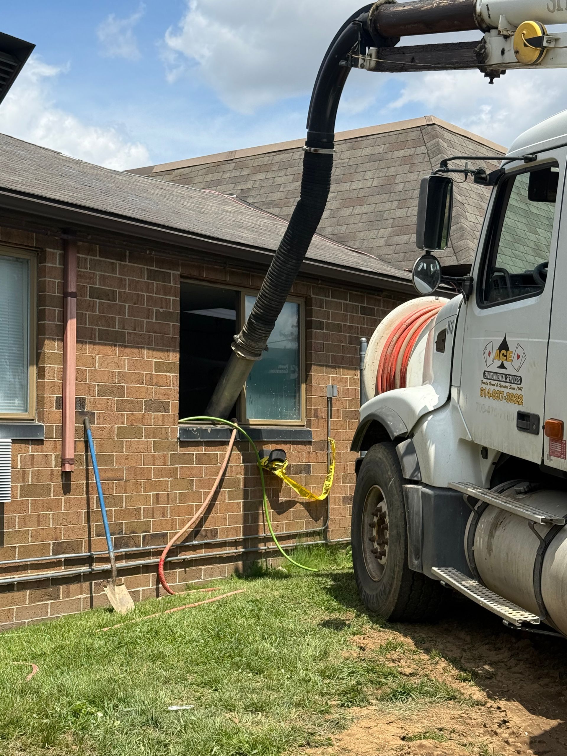 Vacuum truck hose cleaning a brick house exterior window and wall