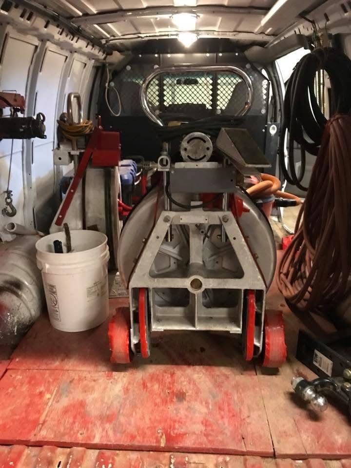 Van interior with welding equipment, hoses, and a red welder on the floor, seen from the rear cargo area