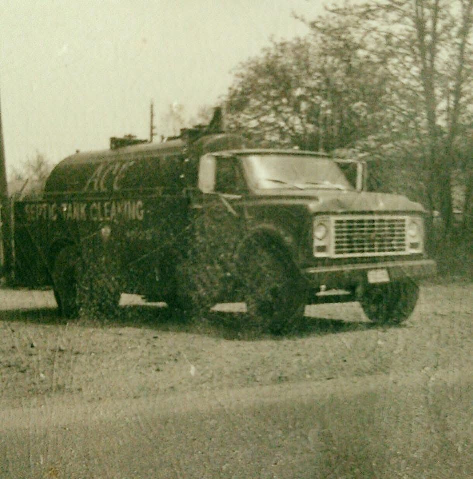 Dark cleaning service truck parked on a roadside beside bare trees