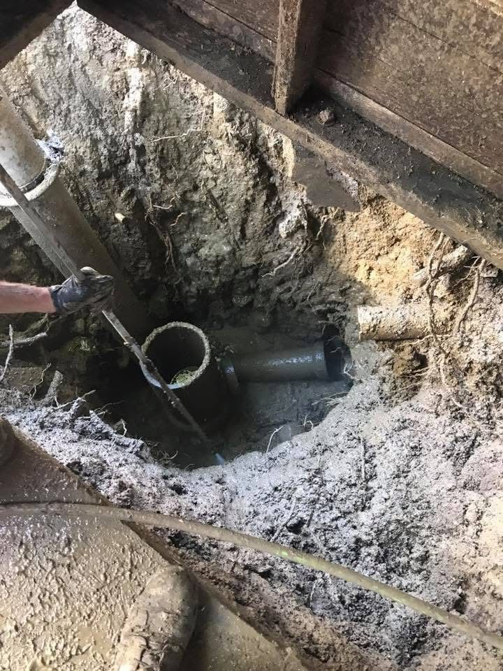 Worker using a hose to spray mud from a deep pit under a wooden structure