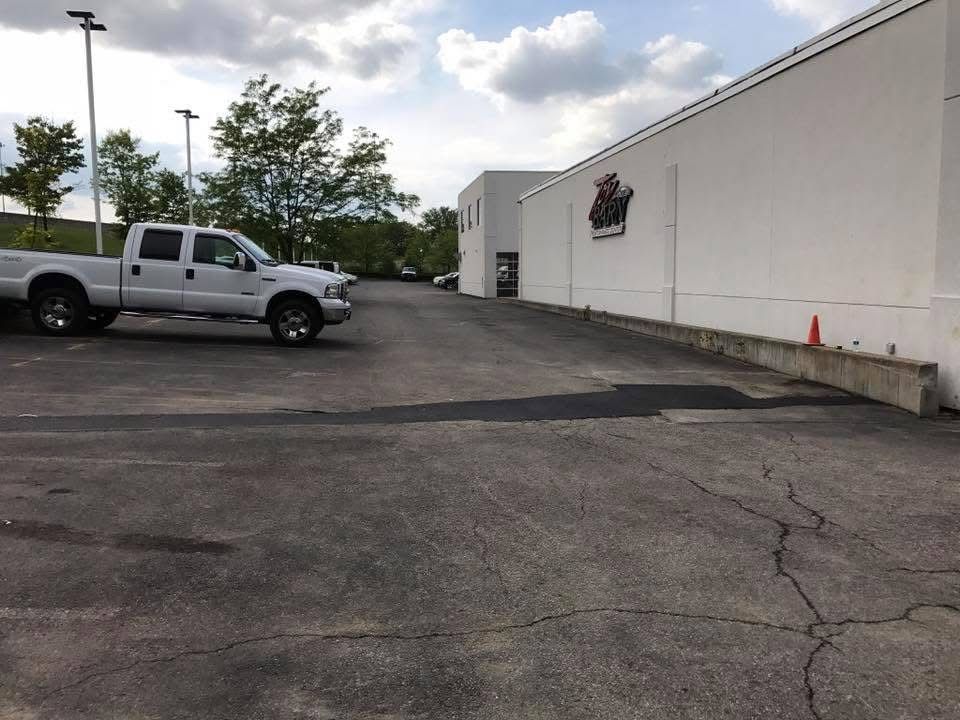 Parking lot beside a white building, with a silver pickup truck and cloudy sky.