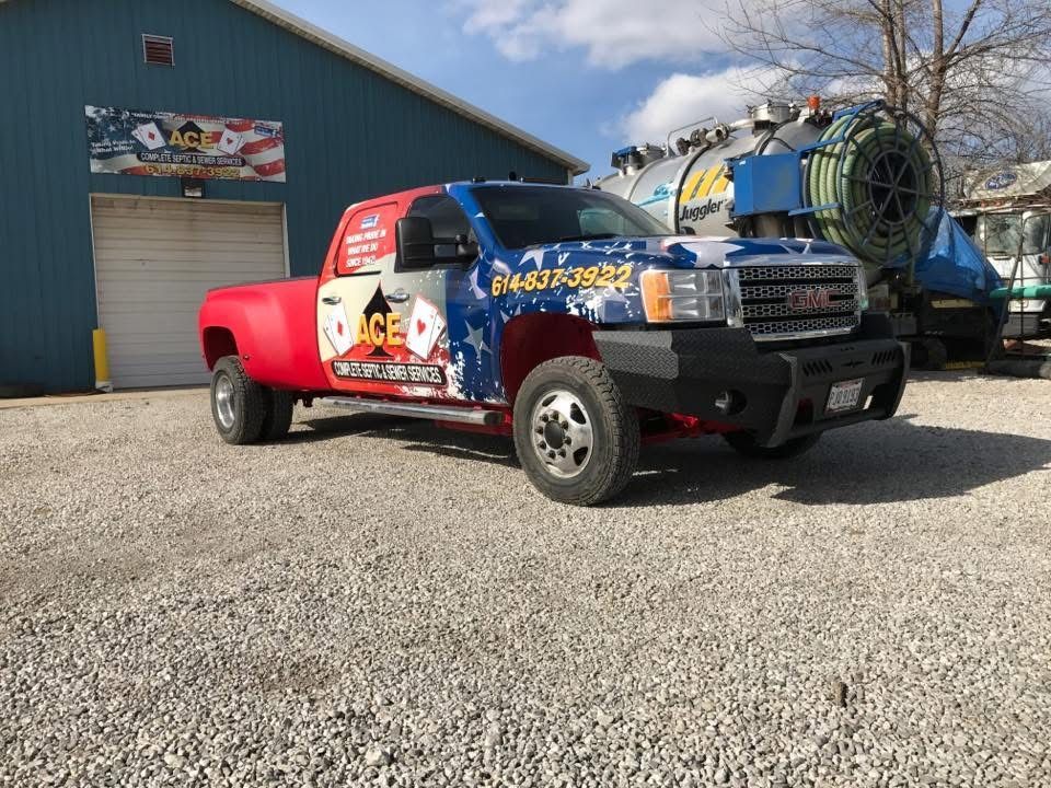 Colorfully wrapped pickup truck parked on gravel outside a blue building on a sunny day