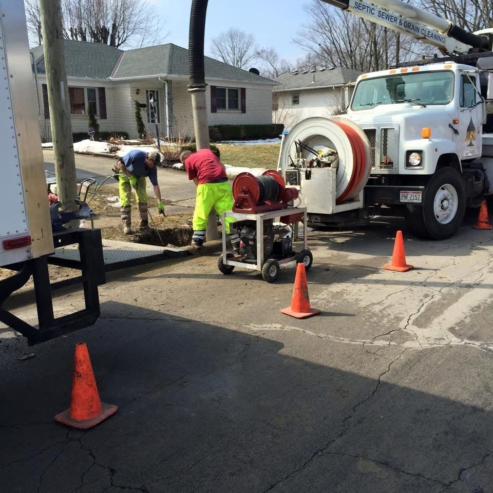 Utility workers repairing a street with cones, trench equipment, and a white truck in a residential area