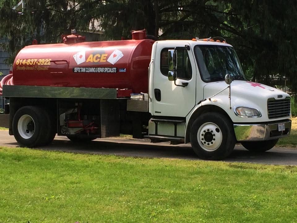 White and red ACE tanker truck parked on grass in a park-like setting