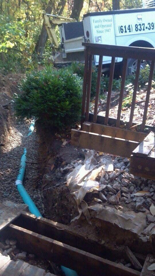 Broken outdoor stairway with a blue pipe, debris pile, and railing beside a truck.