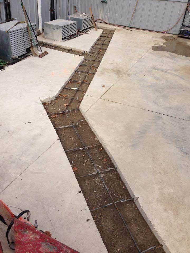 Outdoor concrete courtyard with a narrow, broken trench running through the middle