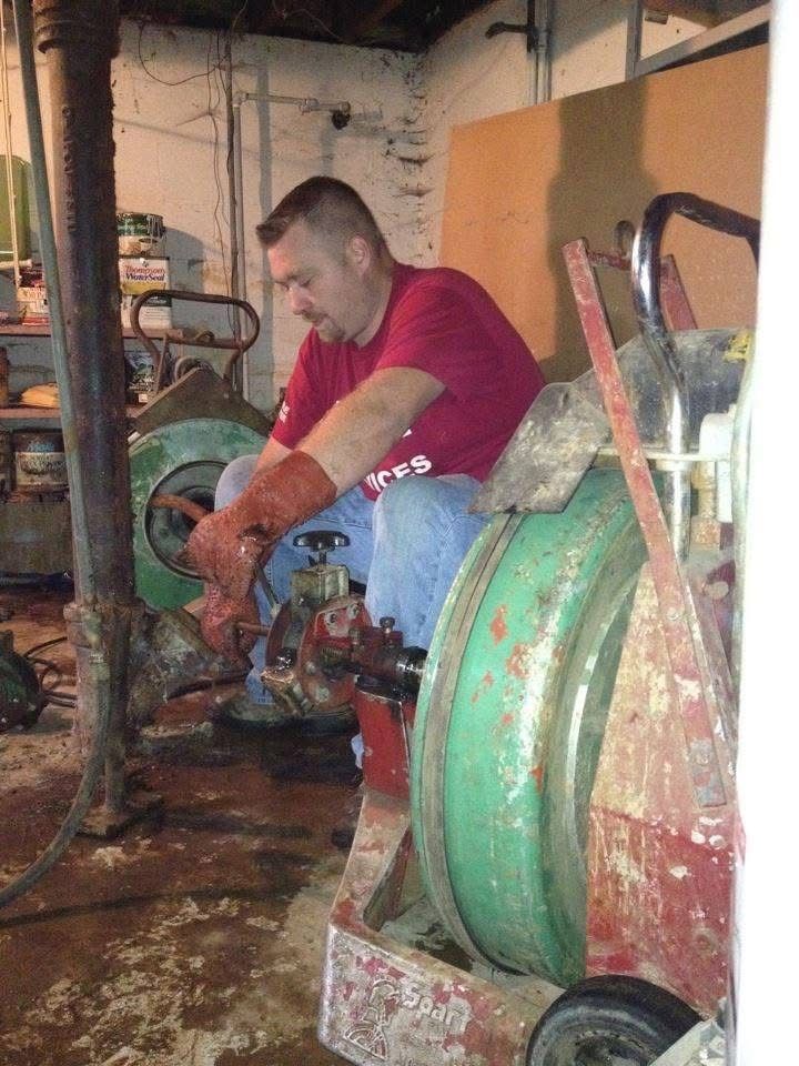 Man in a red shirt working on a large green industrial machine in a workshop