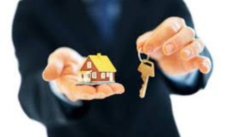 a realtor is holding a small house and keys in his hands .