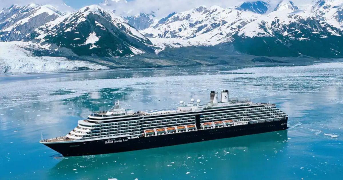 Cruise ship sailing through icy blue water with snow-covered mountains in the background
