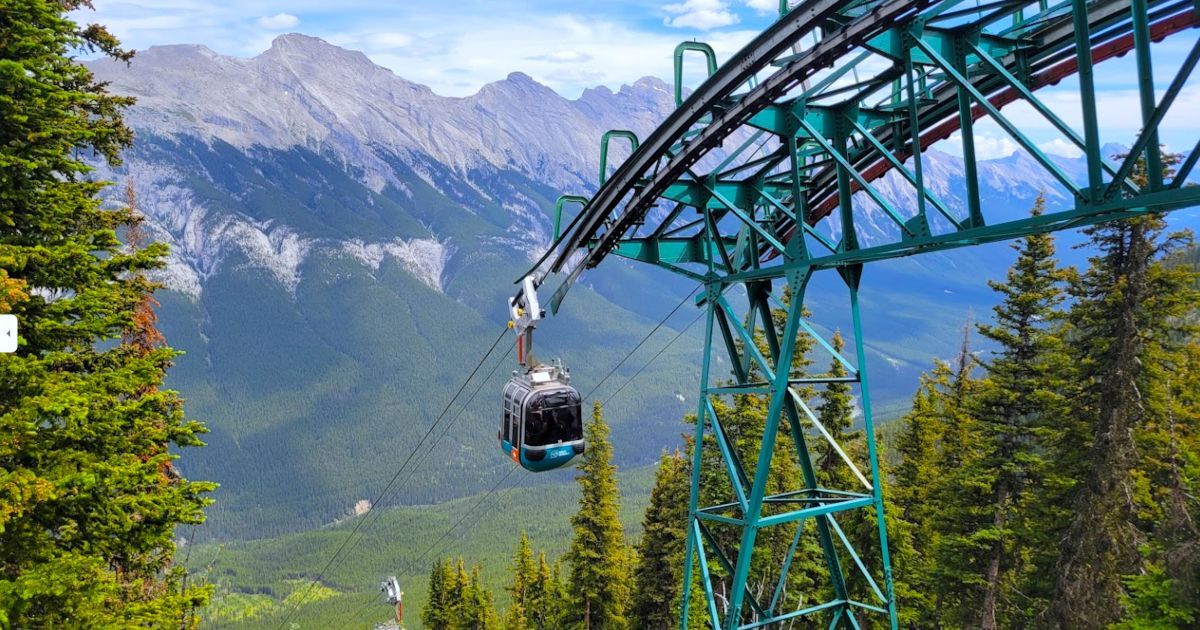 Cable car gliding along a blue-green mountain tower over a forested alpine valley