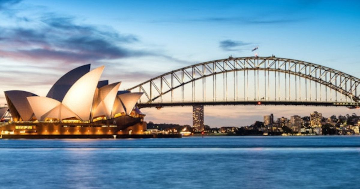Sydney Opera House and Harbour Bridge at sunset over calm blue water