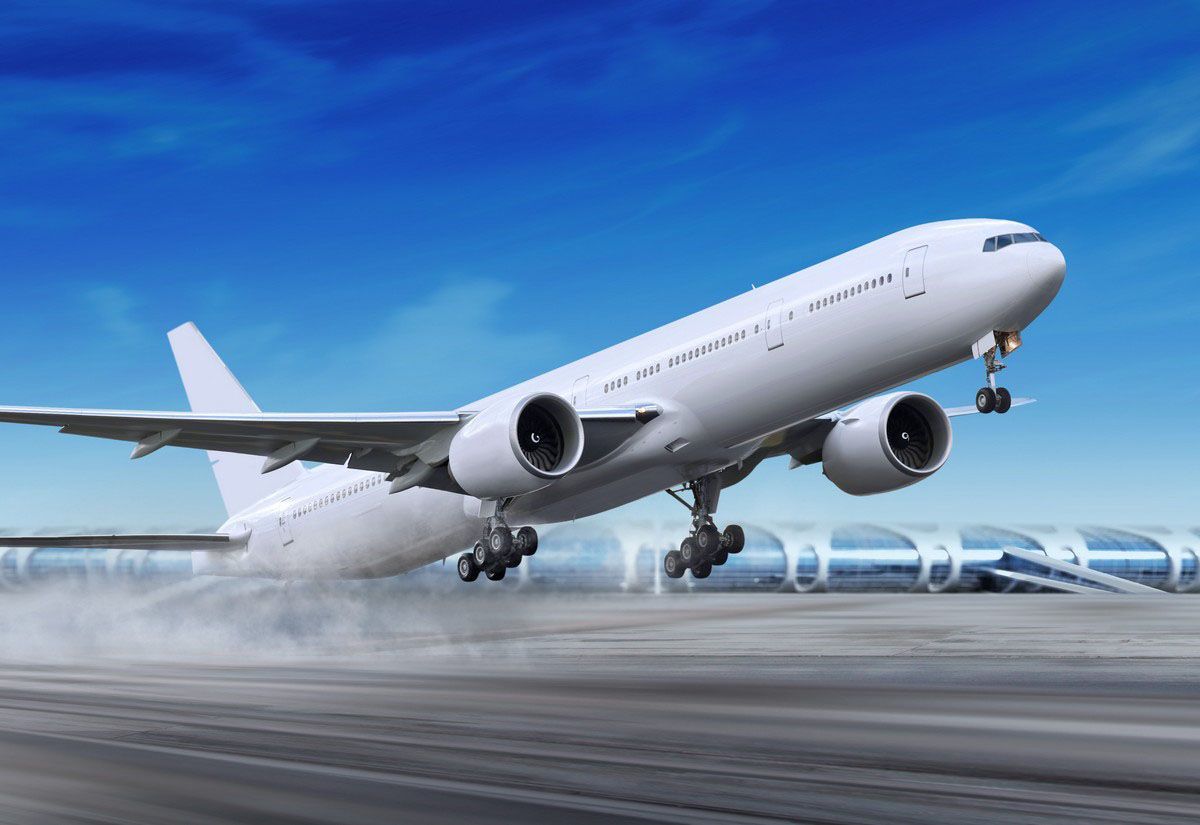 Airplane taking off from a runway, wheels lifting with water spray under a blue sky.