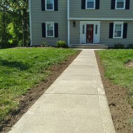 There is a concrete walkway leading to the front of a house.