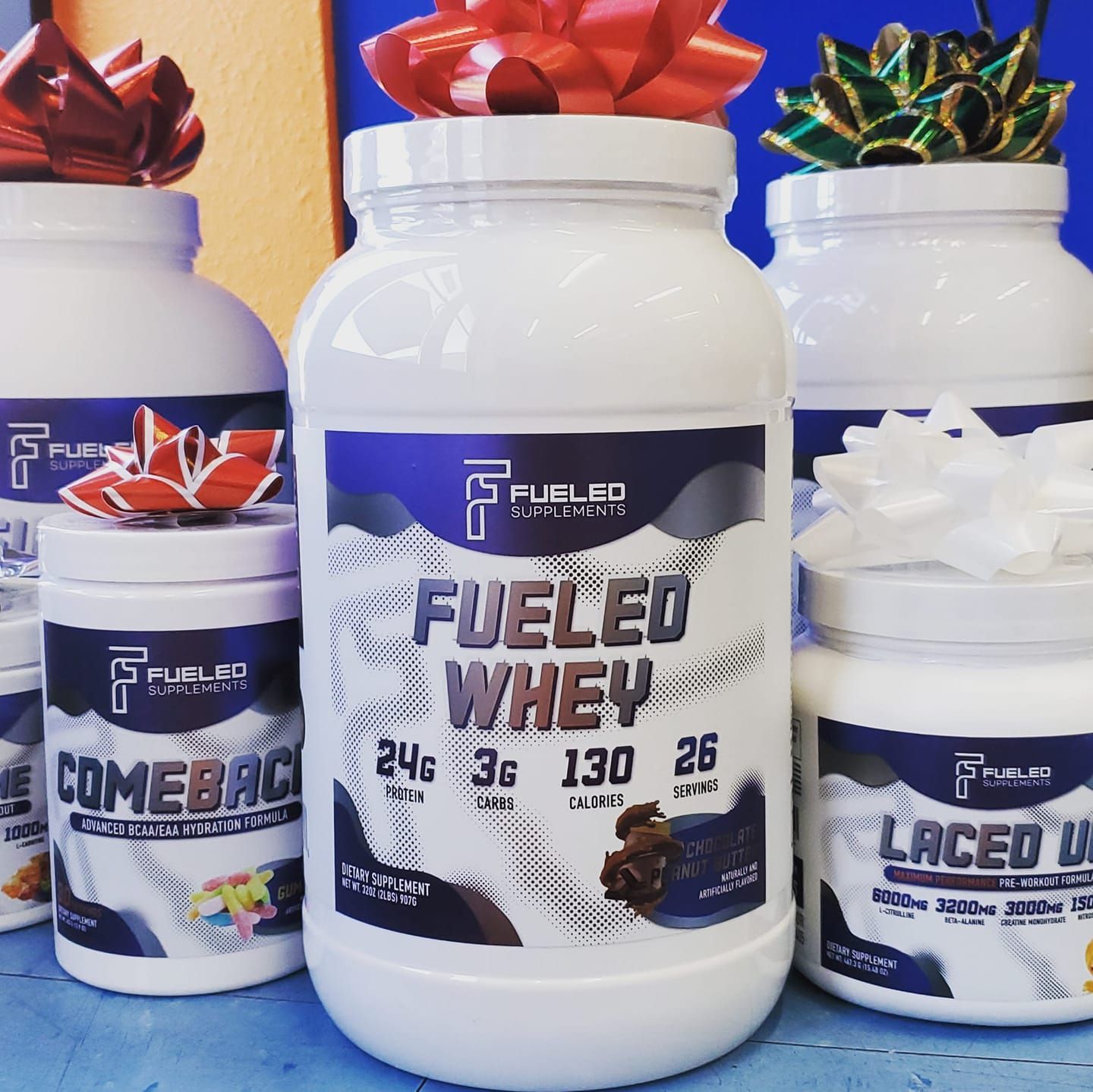 A bottle of fueled whey is surrounded by other bottles.