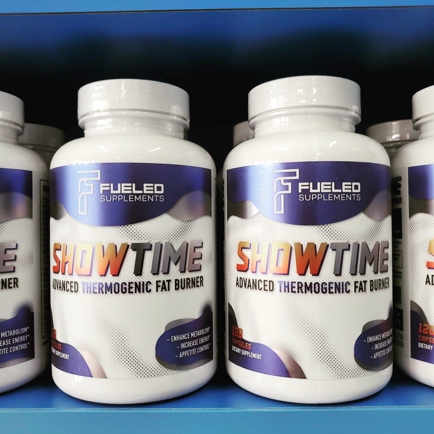 Bottles of showtime are lined up on a blue shelf.