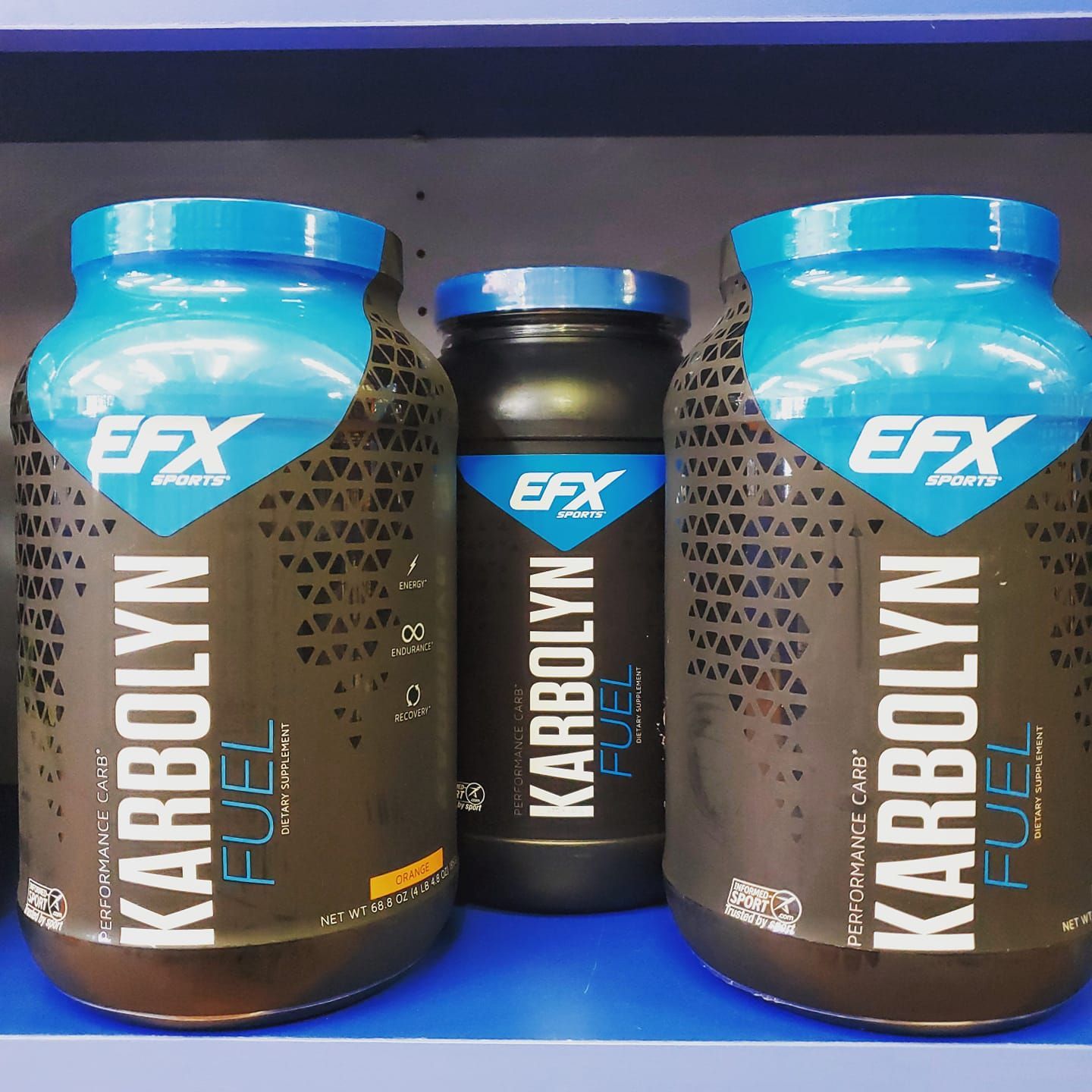 Three bottles of efx karbolyn fuel on a blue shelf.