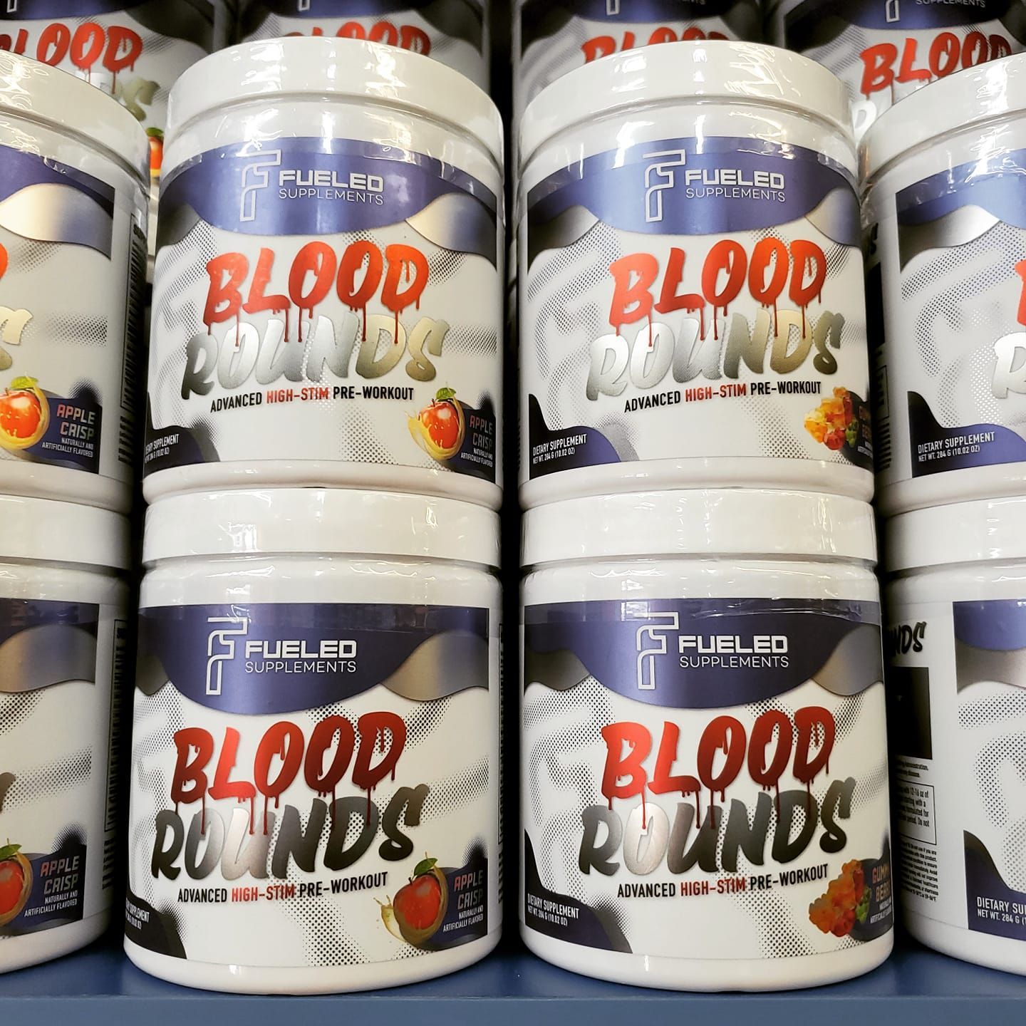 Sports supplements are stacked on top of each other on a shelf.