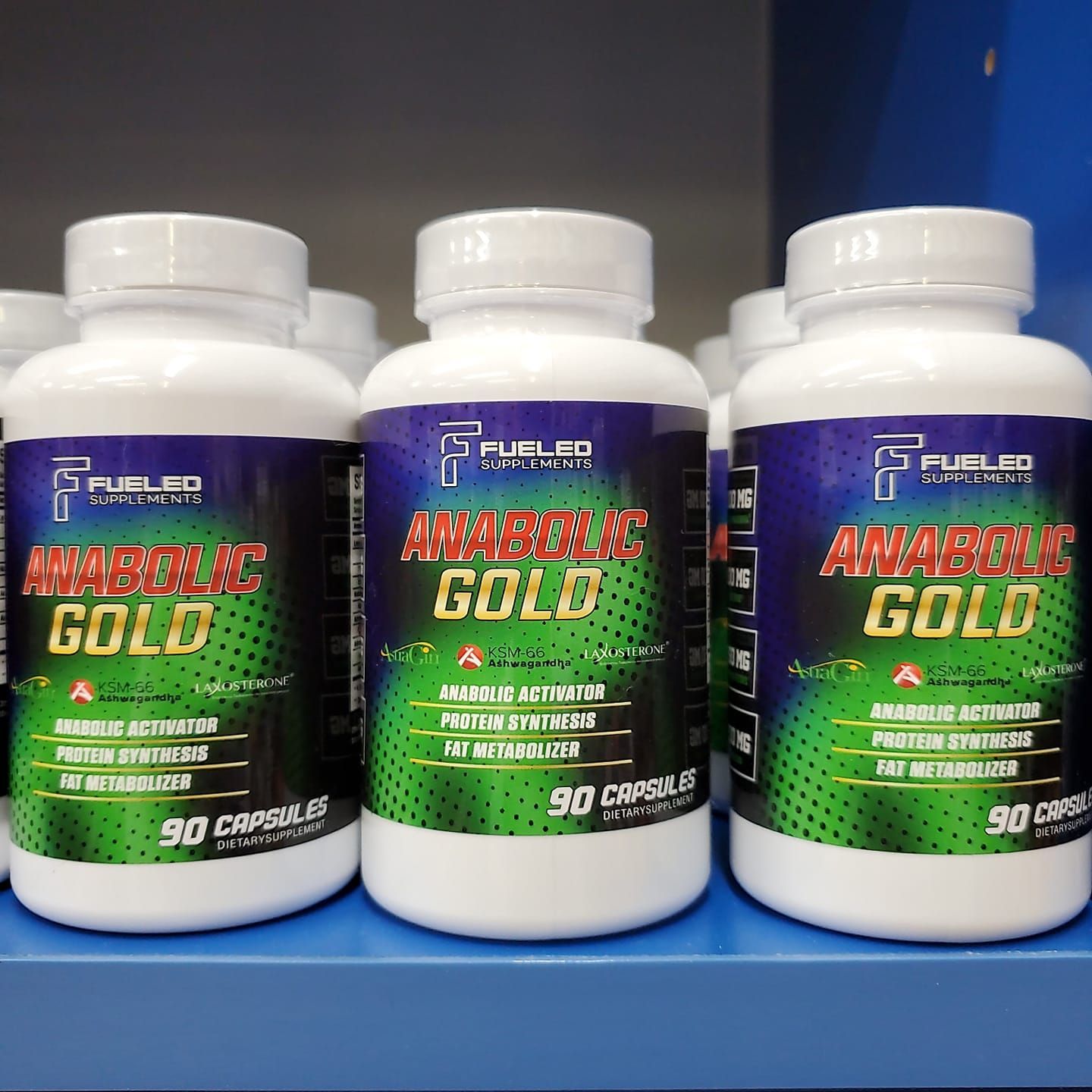 Three bottles of anabolic gold are lined up on a shelf.