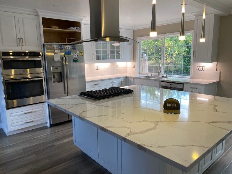 A kitchen with white cabinets , stainless steel appliances and a large island.