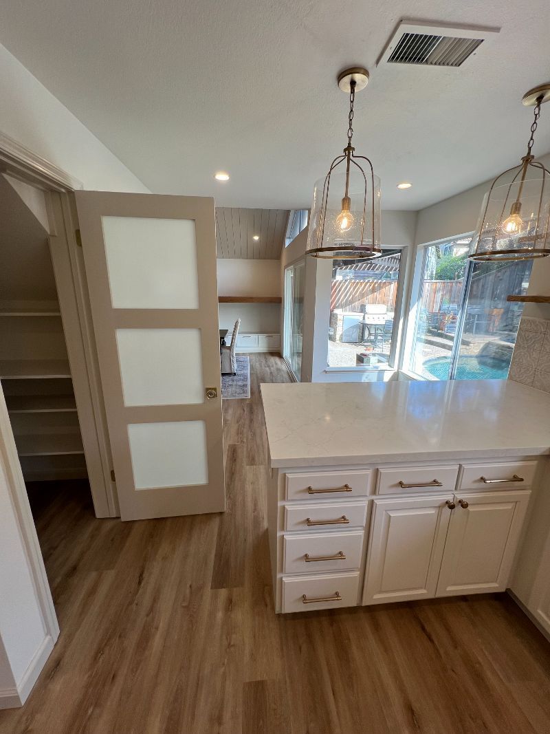 A kitchen with white cabinets and a large island in the middle of the room.