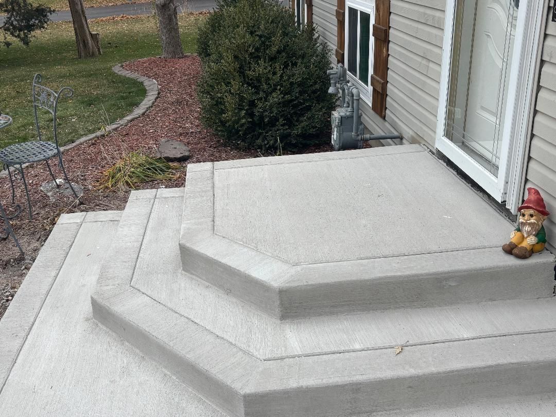Concrete front steps lead to a house door, with a small garden gnome sitting on the right side.