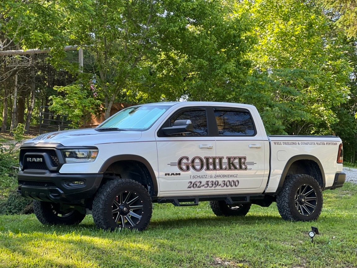 a white truck is parked in the grass in front of a house