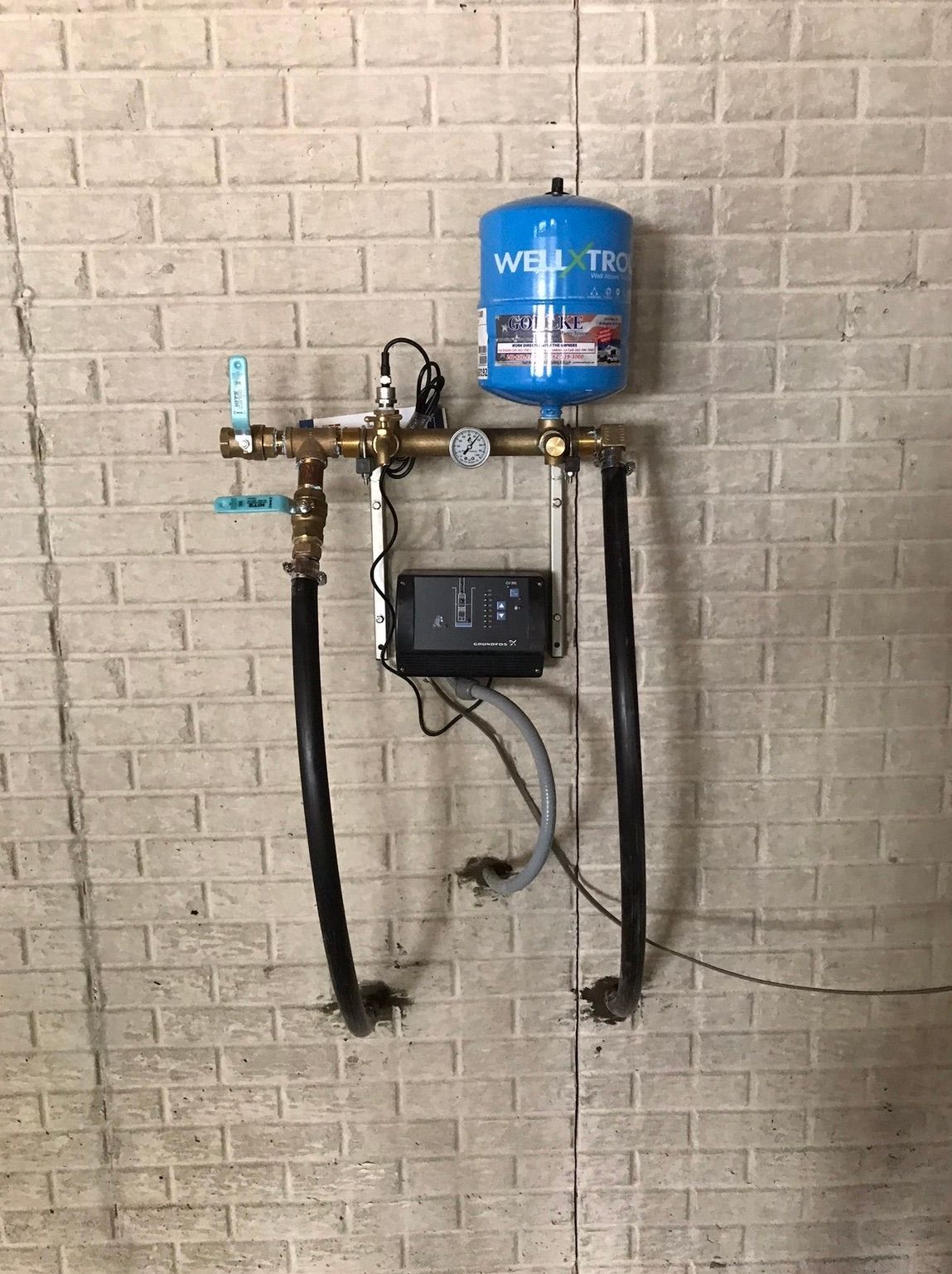 a blue water tank is hanging on a white brick wall