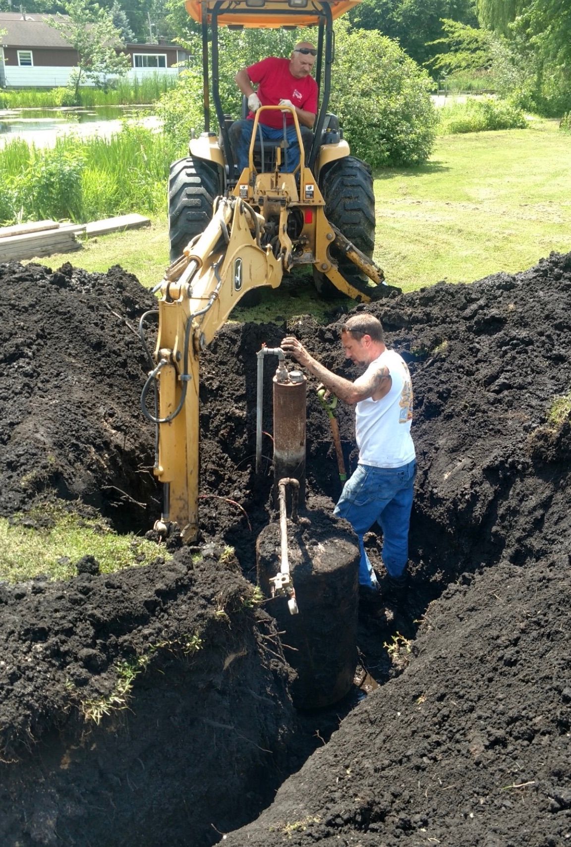 a man is digging a hole with a tractor in the background