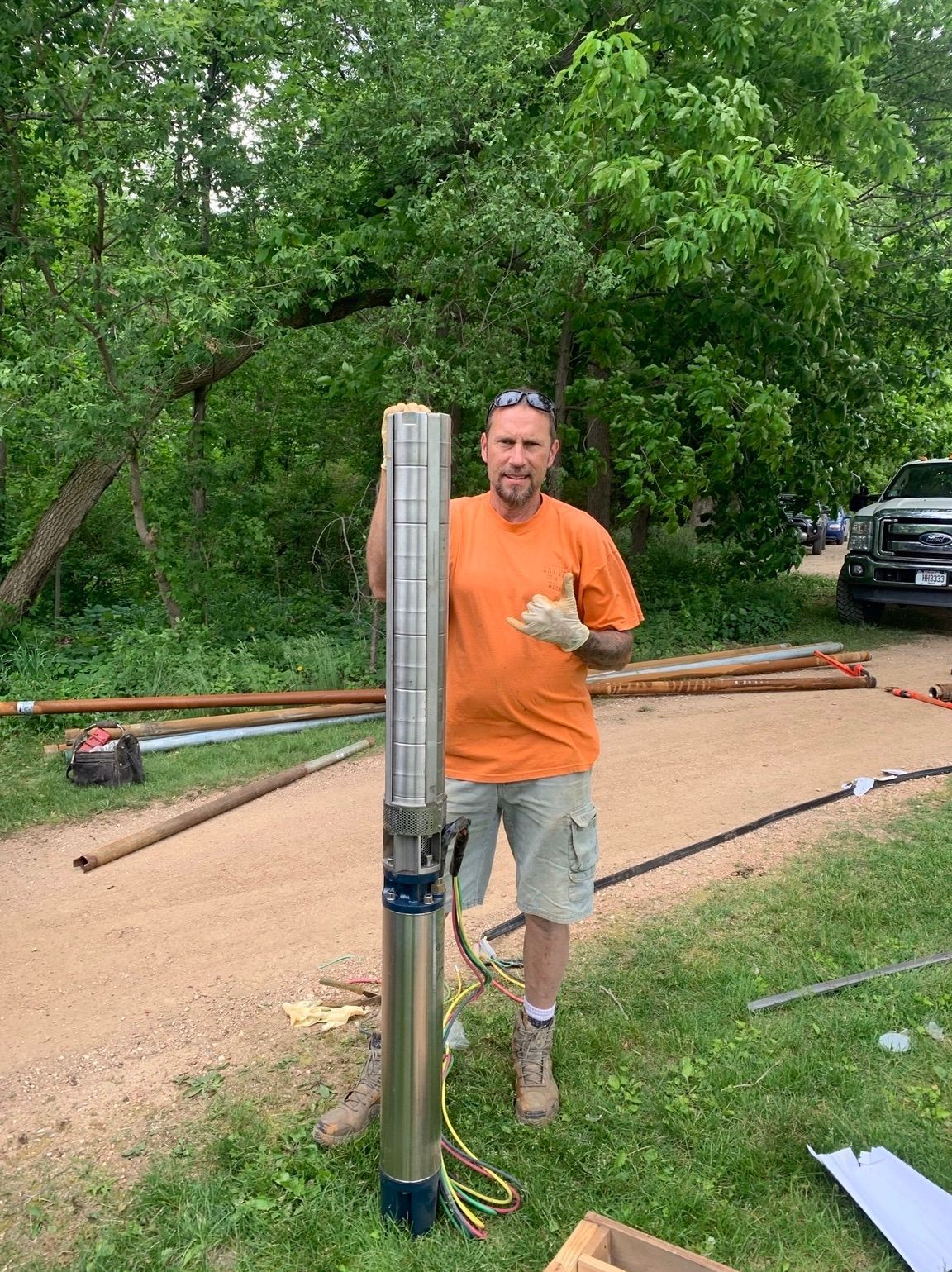 a man is standing in the grass holding a large water pump