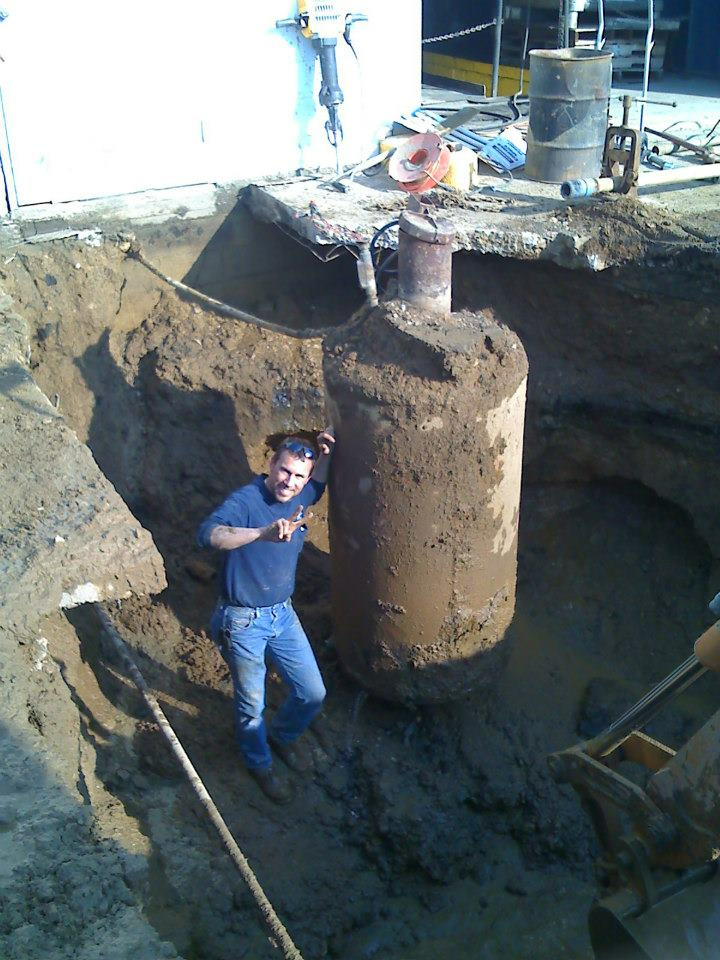 a man in a blue shirt is standing in a hole in the ground