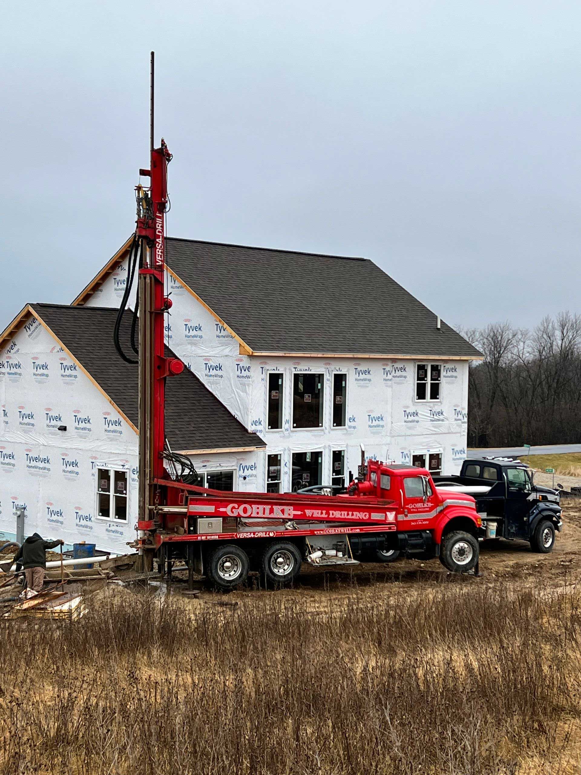 a red truck is parked in front of a house under construction