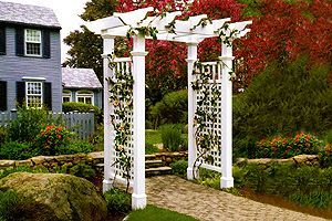 A white pergola is in the middle of a garden in front of a house.