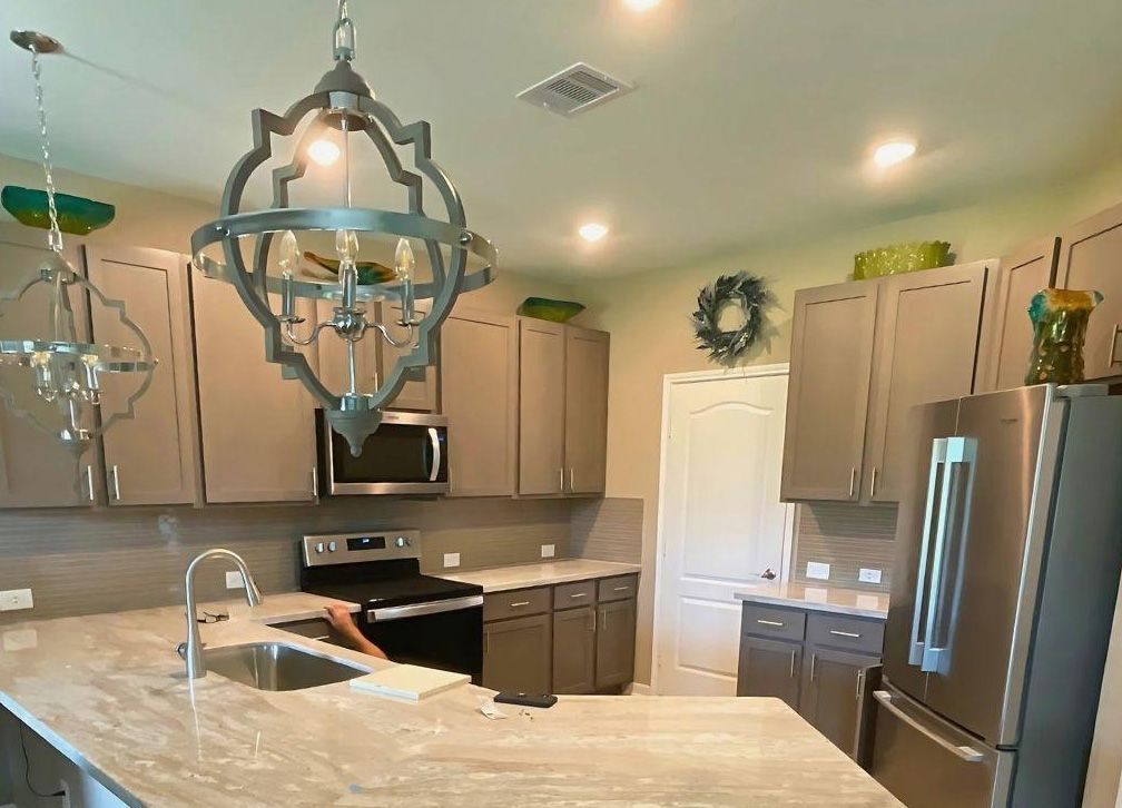 Kitchen with gray cabinets, stainless steel appliances, and a decorative light fixture.