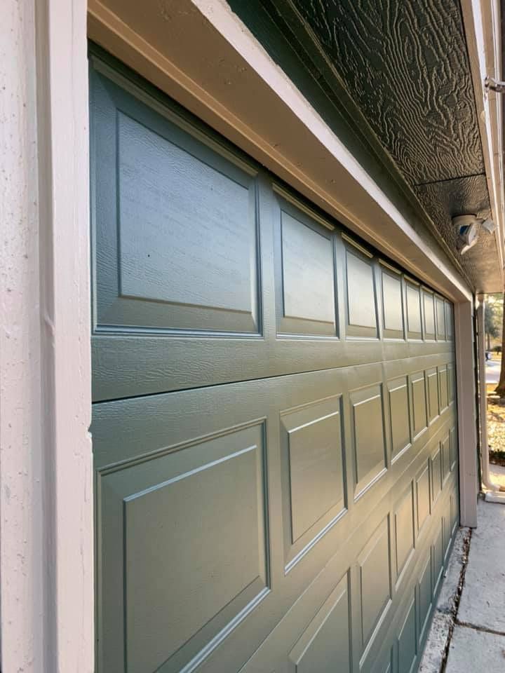 Green garage door with panels, close-up, beige trim.