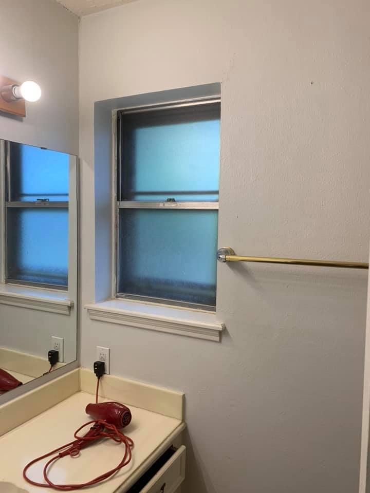 Bathroom interior with a window, mirror, and hairdryer on the counter.