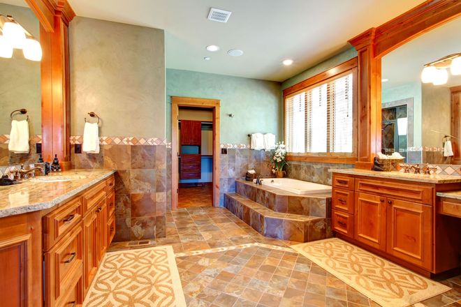 Spacious bathroom with wooden cabinets, tile floor, built-in tub, large mirrors, and a neutral color scheme.