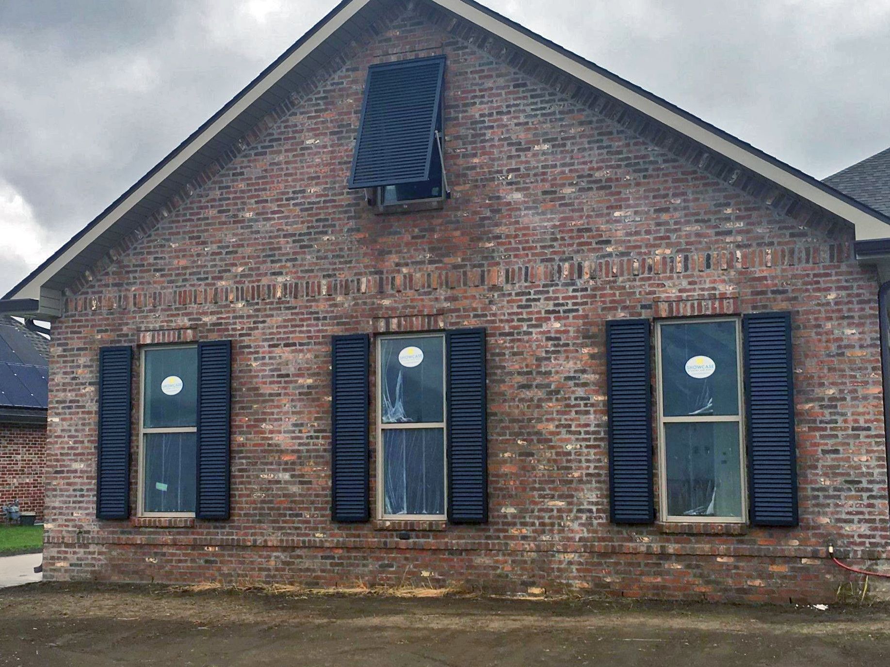 A brick house with black shutters on the windows