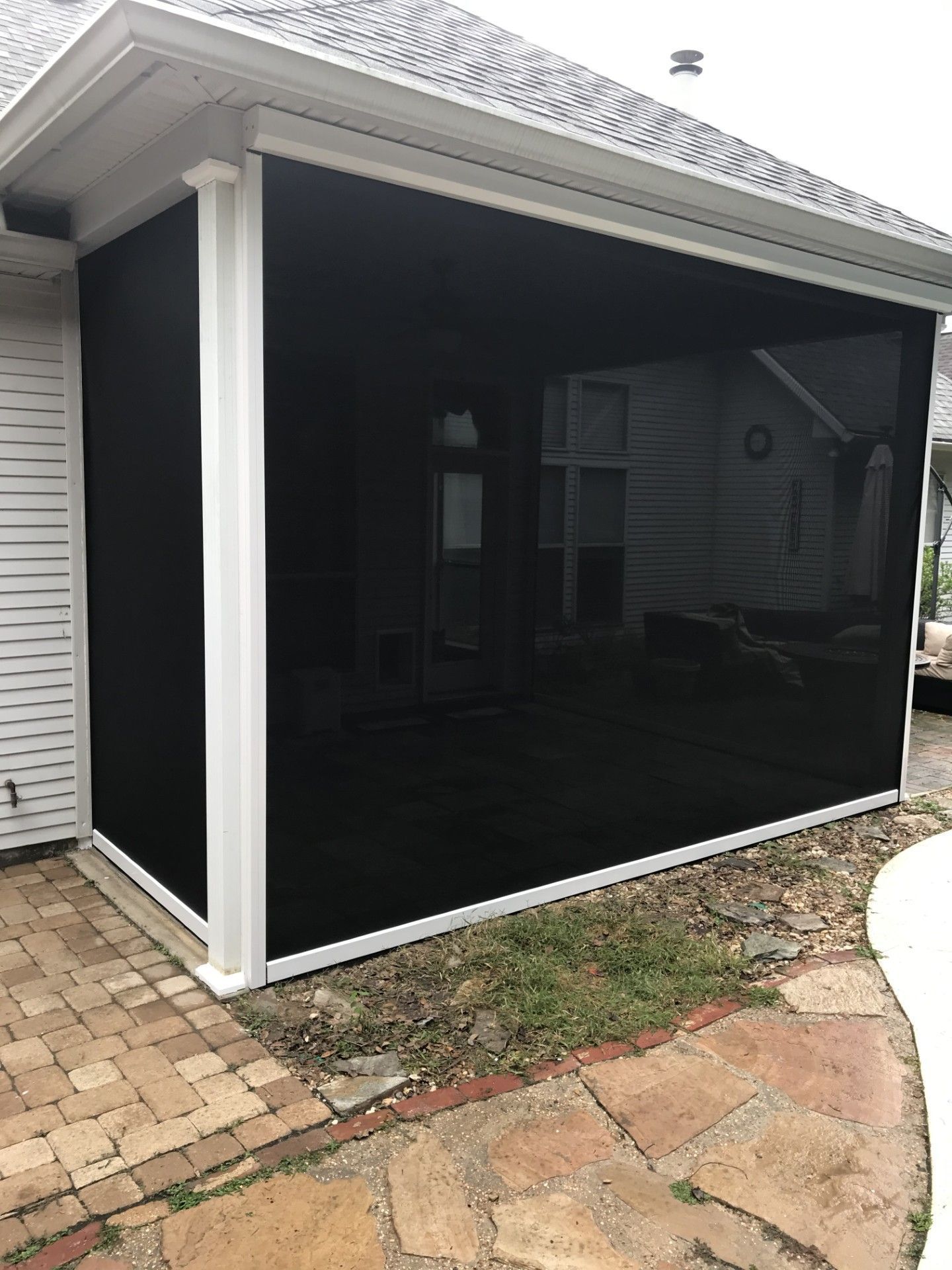 A screened in porch with a black screen on the side of a house.