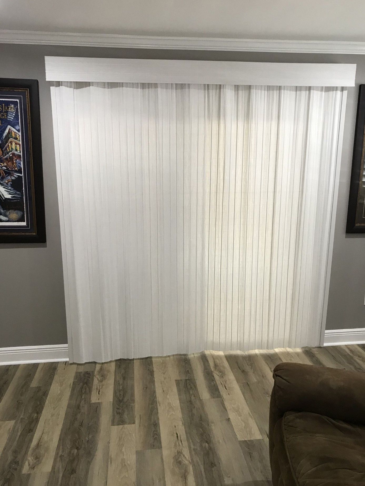 A living room with a couch and a window with white blinds.