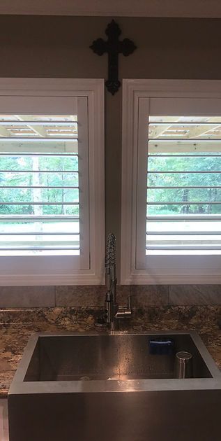 A kitchen sink with a cross hanging on the wall above it.