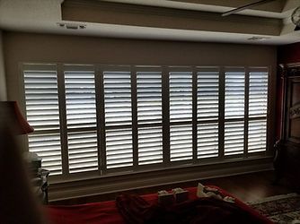 A living room with a large window with shutters on it.