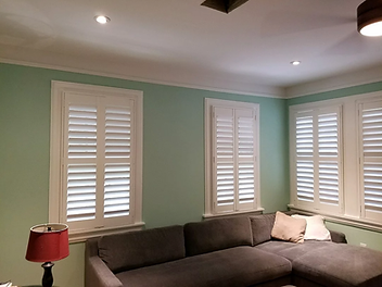 A living room with a couch and shutters on the windows