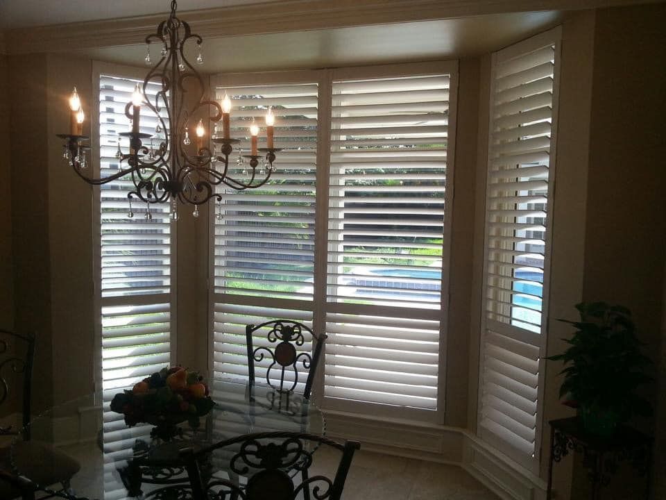 A dining room with shutters on the windows and a chandelier