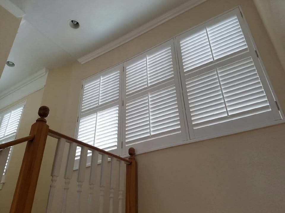 A staircase with white shutters on the windows and a wooden railing.