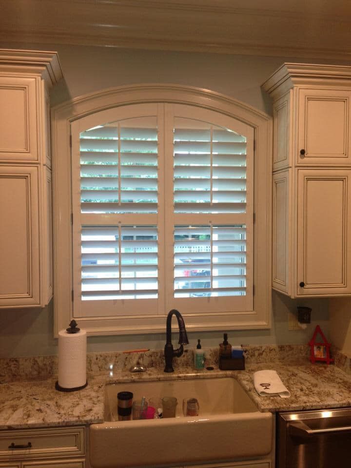 A kitchen with a sink and a window with shutters on it.